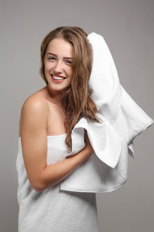 Schöne junge Frau, die Haar mit Tuch nach Dusche auf grauem Hintergrund abwischt stockbilder Schöne junge Frau, die Haar mit Tuch nach Dusche auf grauem Hintergrund abwischt stockbilder