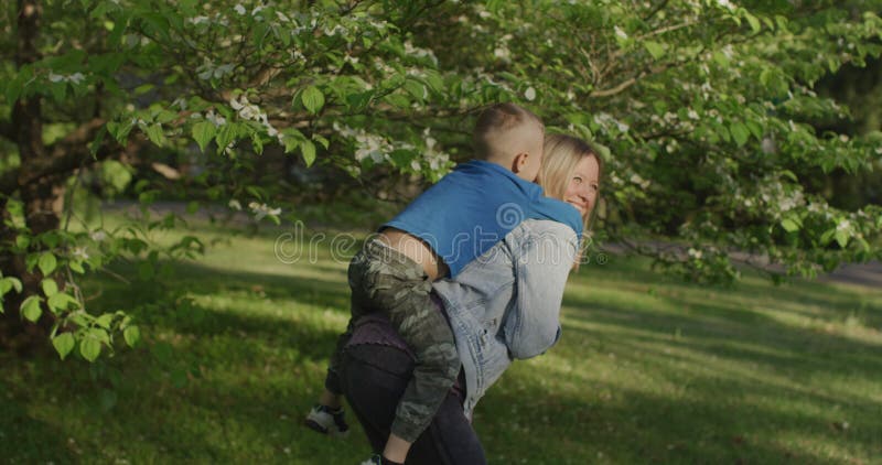 Schöne junge Frau, die Spaß mit ihrem kleinen Jungen hat. kleine Junge auf seiner Mutterrückseite stock footage