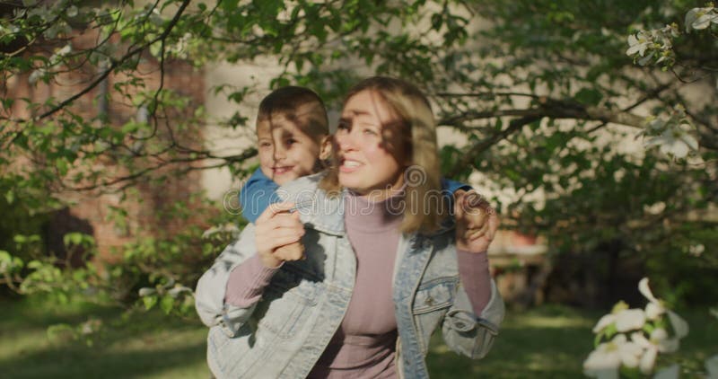 Schöne junge Frau, die Spaß mit ihrem kleinen Jungen hat. kleine Junge auf seiner Mutterrückseite stock footage
