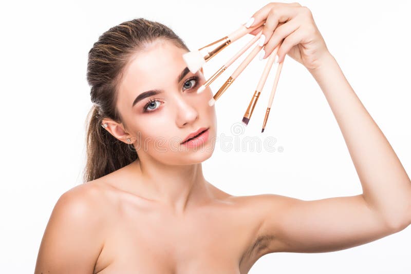 Schöne junge Frau hält die Make-upbürsten nahe attraktivem Gesicht Mode-Modell, das über weißem Hintergrund aufwirft lizenzfreie stockfotos Schöne junge Frau hält die Make-upbürsten nahe attraktivem Gesicht Mode-Modell, das über weißem Hintergrund aufwirft lizenzfreie stockfotos