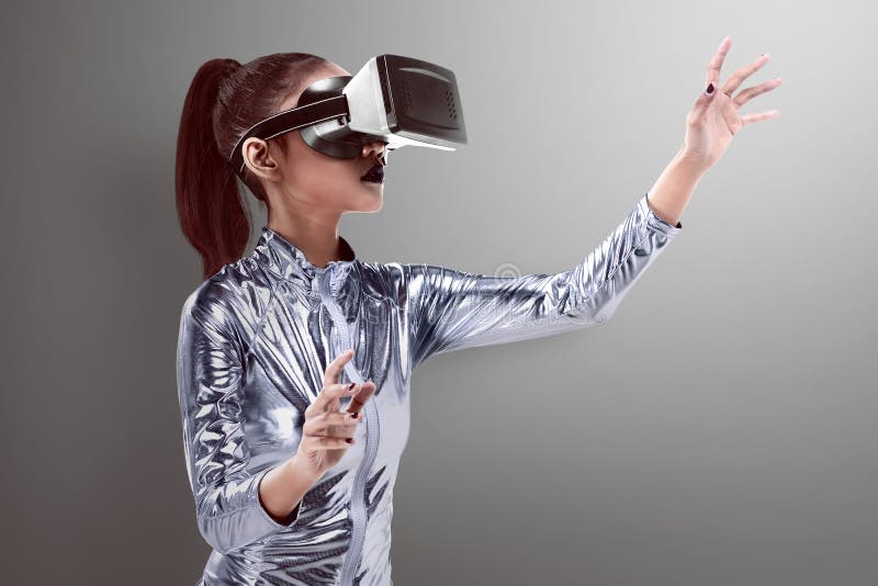 Schöne junge Frau im silbernen Latexkostüm und IN VR-Kopfhörer