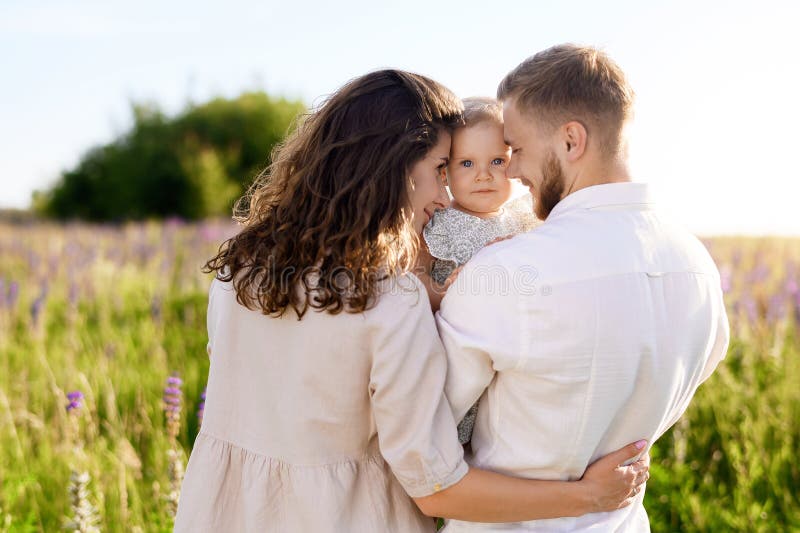 Schöne junge kaukasische Familie Vater und Mutter umarmt ein hübsches Mädchen lizenzfreie stockfotografie