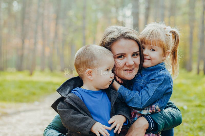 Schöne junge Mutter mit Tochter und Sohn gehen im Herbstpark Nahbild stockfotografie Schöne junge Mutter mit Tochter und Sohn gehen im Herbstpark Nahbild stockfotografie