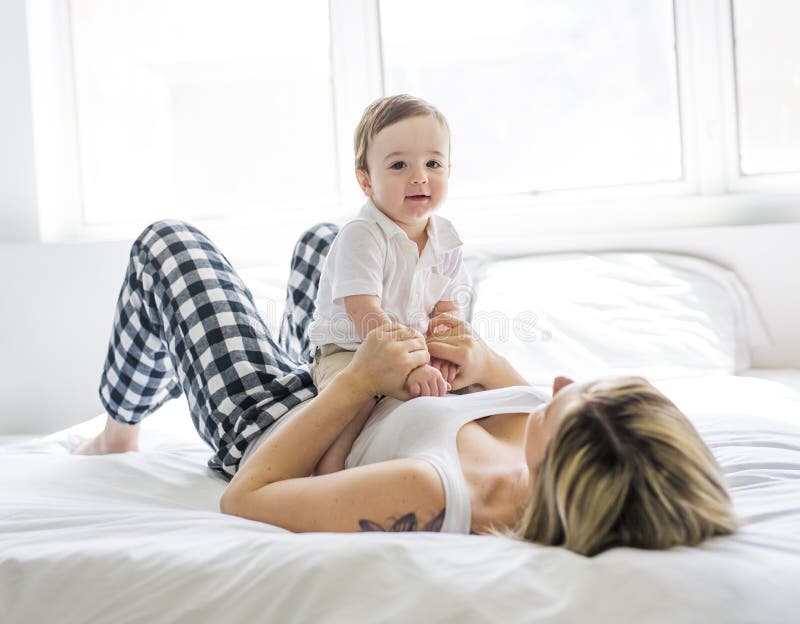 Schöne junge Mutter und Sohn, die zusammen auf einem Bett liegt stockbilder