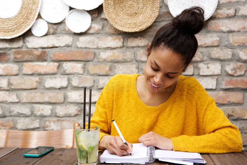 Schöne junge Schreibensanmerkungen der schwarzen Frau am Café