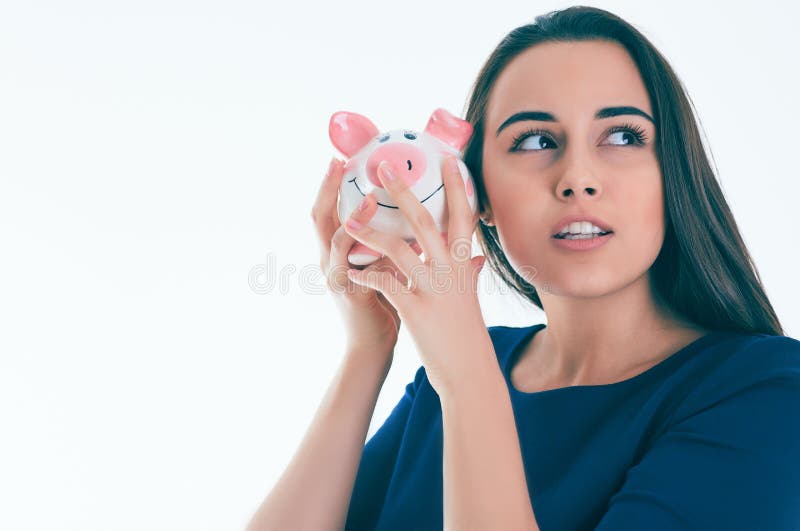 Schöne kaukasische Brunettefrau hört auf den Ton von coinsin ein piggybank und Träume stockfotos Schöne kaukasische Brunettefrau hört auf den Ton von coinsin ein piggybank und Träume stockfotos