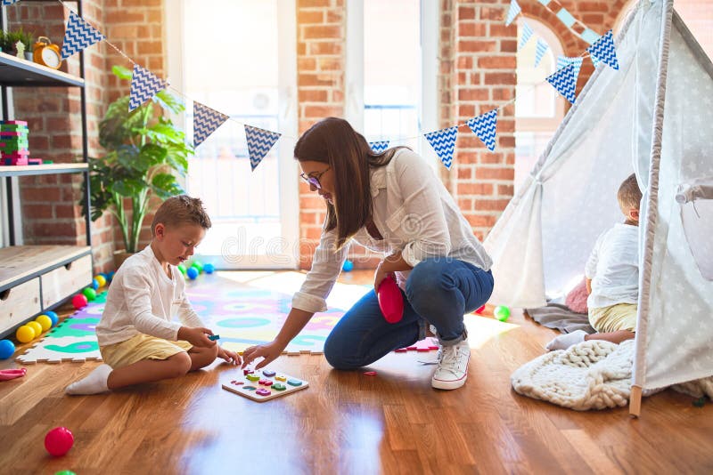 Schöne Lehrer und Kleinkind lernen Mathematik mit Zahlen Puzzle-Spiel um viele Spielzeuge im Kindergarten lizenzfreie stockfotografie