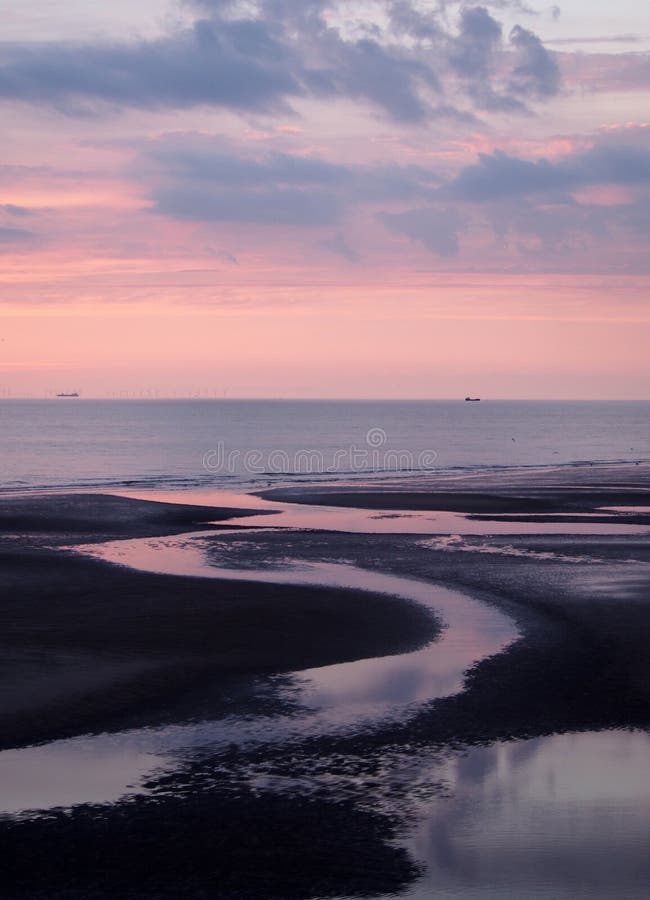 Schöne purpurrote Dämmerung über einem ruhigen See mit Wasser auf dem Strand, der bunte Sonnenuntergangwolken reflektiert stockfoto Schöne purpurrote Dämmerung über einem ruhigen See mit Wasser auf dem Strand, der bunte Sonnenuntergangwolken reflektiert stockfoto