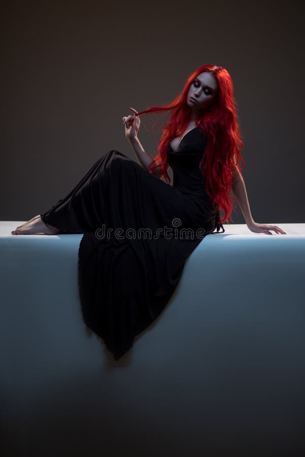 Schöne rote behaarte Frau im schwarzen Kleid
