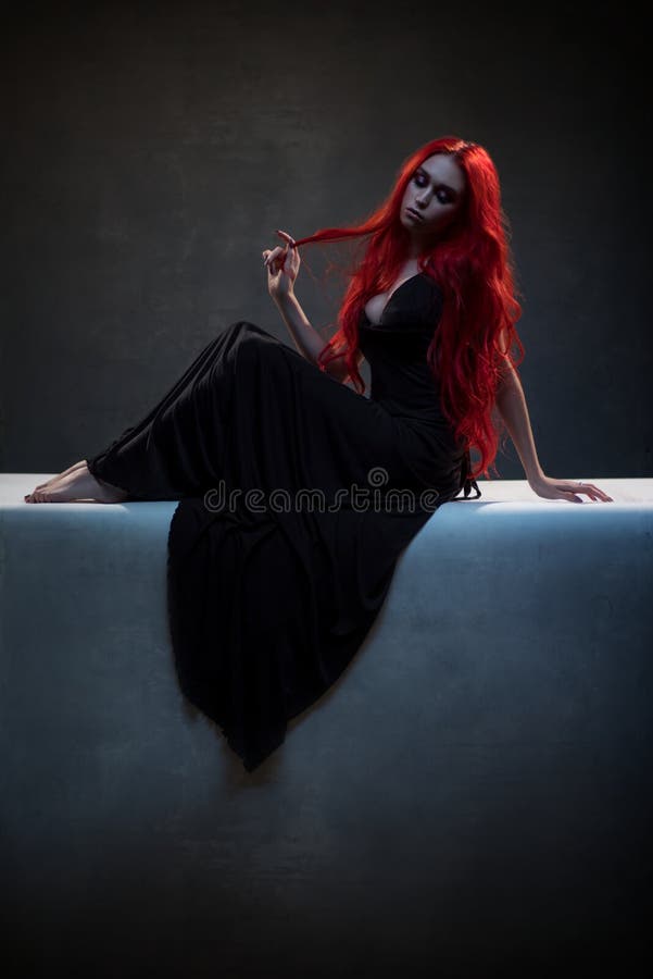 Schöne rote behaarte Frau im schwarzen Kleid