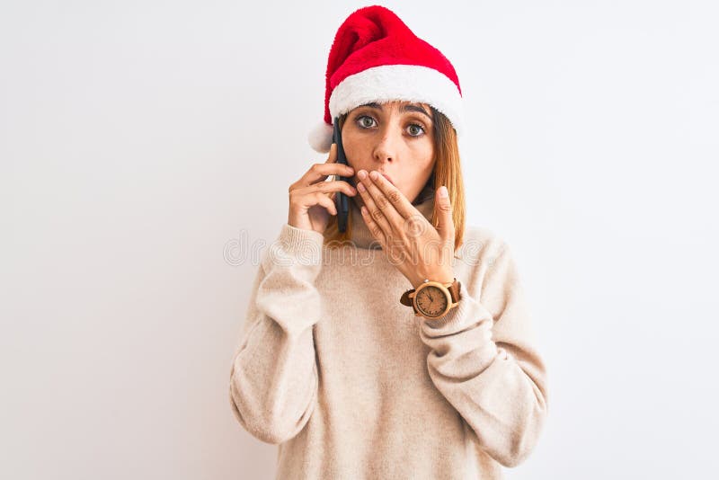 Schöne Rotkopffrau mit Weihnachtsmütze auf Smartphone-Klappe mit Hand schockiert mit Scham für Fehler stockfotografie