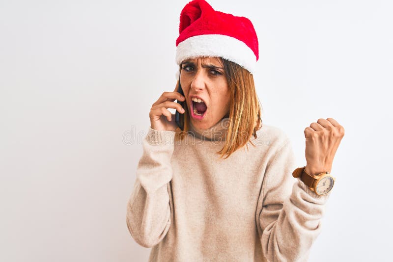Schöne Rotkopffrau mit Weihnachtsmütze auf Smartphone verärgert und frustriert schreien mit Wut verrückt und schreiend lizenzfreies stockbild