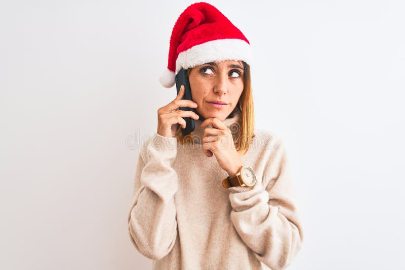 Schöne Rotkopffrau mit Weihnachtsmütze reden auf Smartphone ernsthaftes Gesicht denken über Frage sehr verwirrte Idee lizenzfreie stockfotos