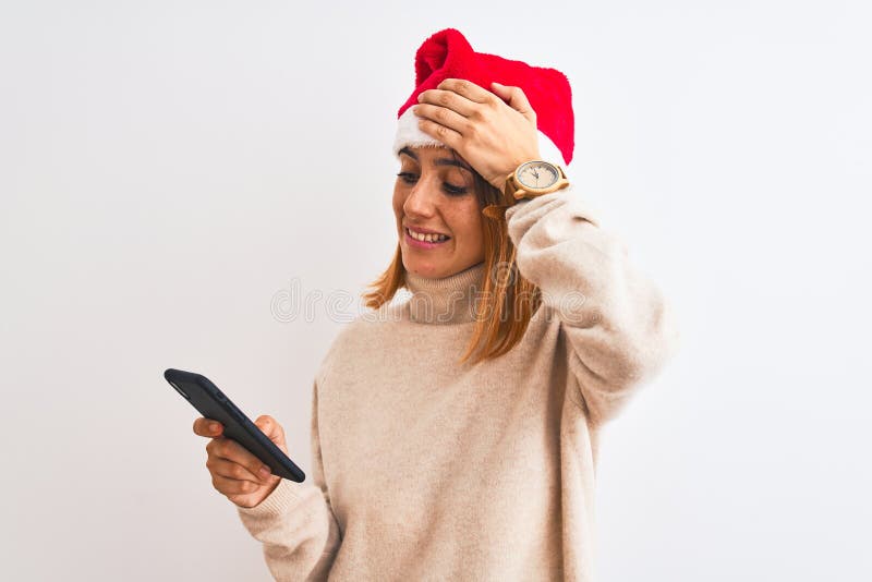 Schöne Rotkopffrau mit Weihnachtsmütze und Smartphone gestresst mit Hand am Kopf schockiert mit Scham und Überraschung stockbild