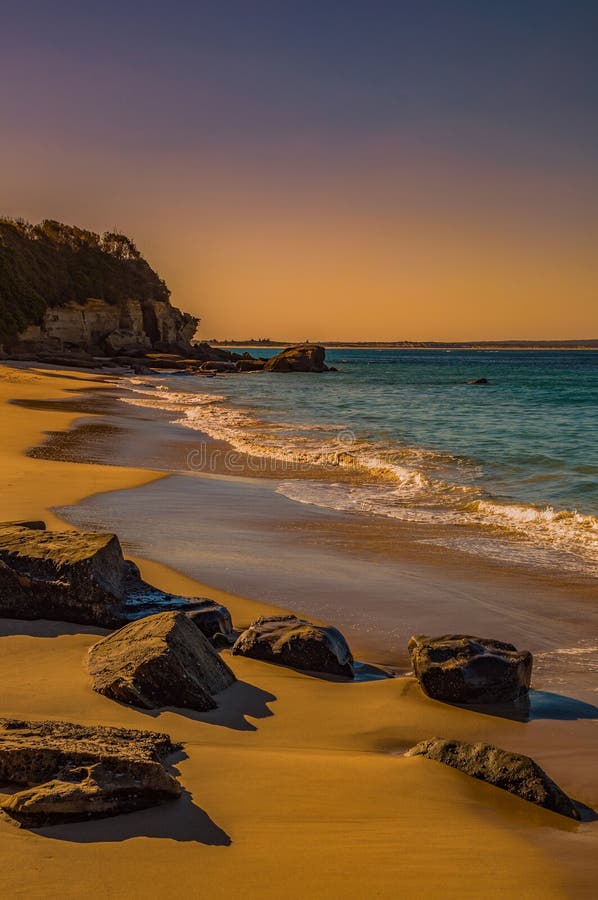 Schöne Sandküste mit Felsen rund und Meer mit Klippen im Hintergrund lizenzfreie stockfotos Schöne Sandküste mit Felsen rund und Meer mit Klippen im Hintergrund lizenzfreie stockfotos