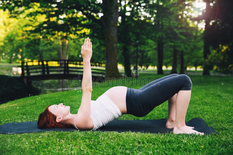 Schöne schwangere Frau, die draußen pränatales Yoga auf Natur tut lizenzfreies stockbild Schöne schwangere Frau, die draußen pränatales Yoga auf Natur tut lizenzfreies stockbild