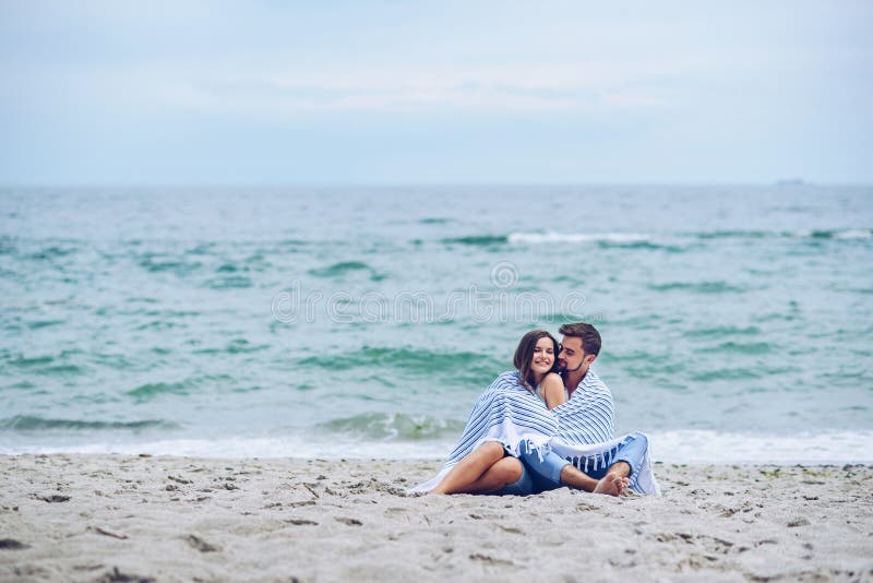 Schöne schwangere Frau und ihr beachtlicher Mann, die sich gegeneinander und bedeckt mit einem weißen gestreiften Plaid lehnt stockfotos Schöne schwangere Frau und ihr beachtlicher Mann, die sich gegeneinander und bedeckt mit einem weißen gestreiften Plaid lehnt stockfotos