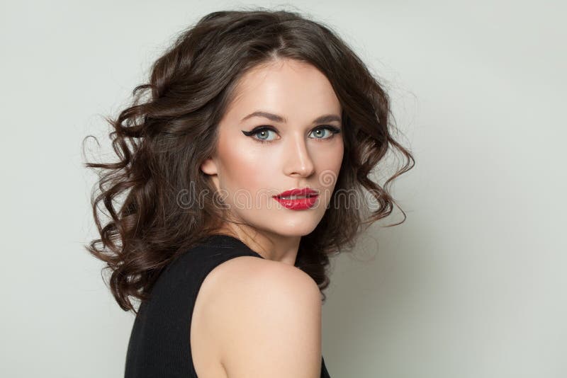 Schöne sexy Frau, die Kamera betrachtet Hübsches Modell mit Make-up und braunem Porträt des gelockten Haares stockbilder