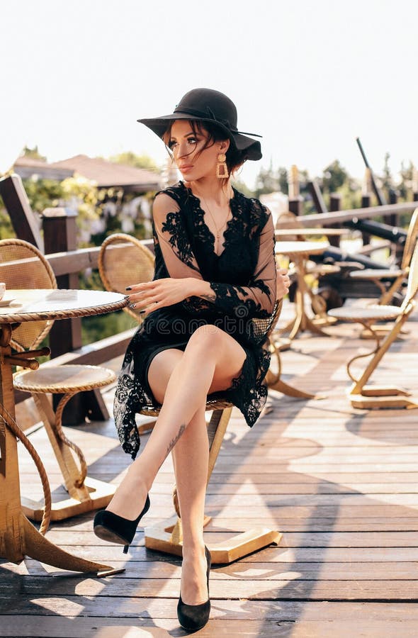Schöne sexy Frau mit dem dunklen Haar im eleganten schwarzen Kleid und im Hut stockfoto Schöne sexy Frau mit dem dunklen Haar im eleganten schwarzen Kleid und im Hut stockfoto
