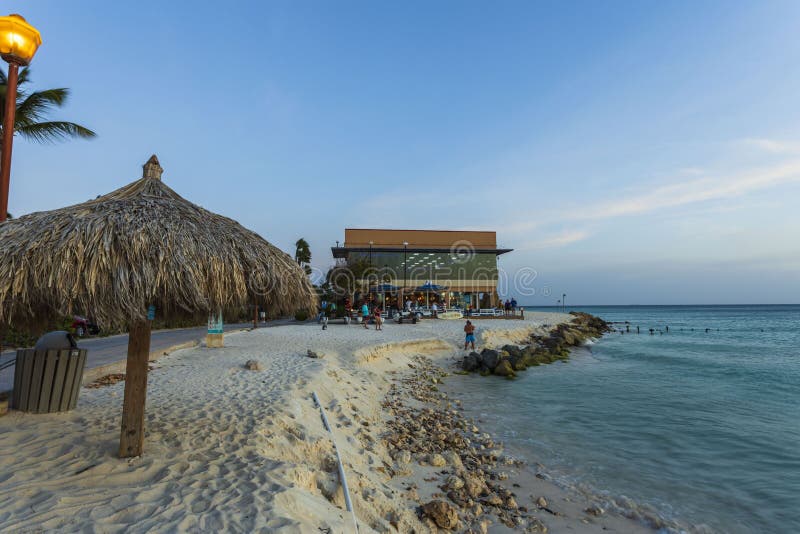 Schöne Sicht auf das Hotelgebäude Touristen auf blauen Sonnenliegen, weißem Sand und Palmen auf blauem Himmel Eagle Beach stockfotos Schöne Sicht auf das Hotelgebäude Touristen auf blauen Sonnenliegen, weißem Sand und Palmen auf blauem Himmel Eagle Beach stockfotos