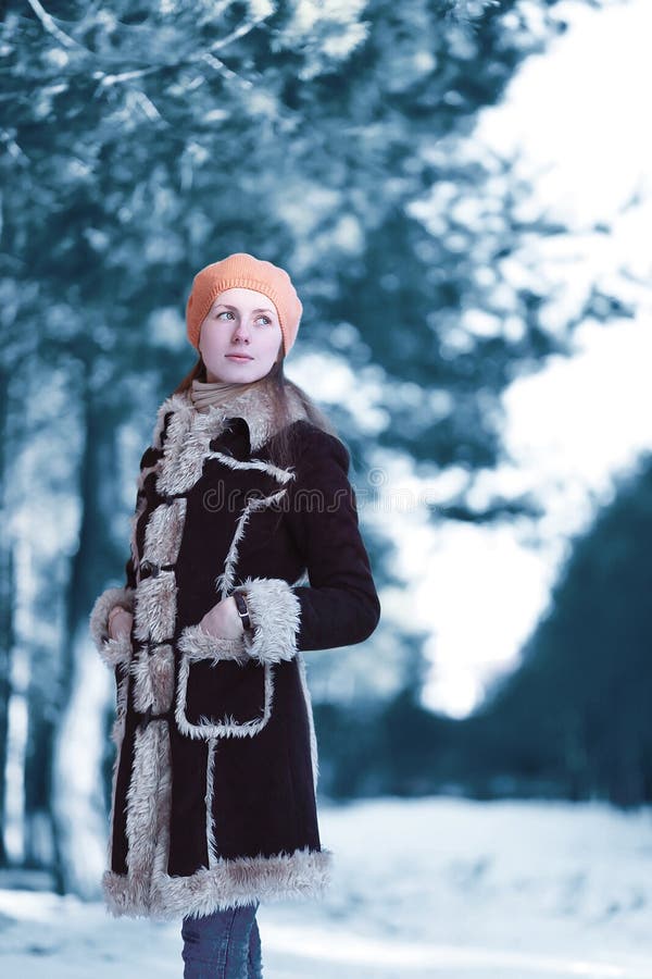 schöne Stellung der jungen Frau schaut weg tragenden braunen Mantelbaretthut im kalten schneebedeckten skandinavischen Wald des W