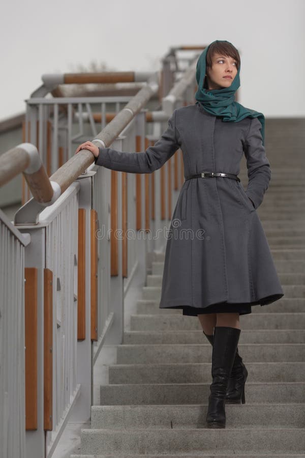 Schöne stilvolle Frau im grauen Mantel, der auf Treppe steht stockfoto Schöne stilvolle Frau im grauen Mantel, der auf Treppe steht stockfoto