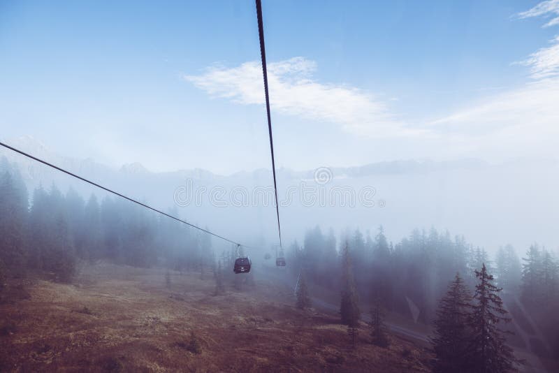 Schöner Blick auf eine lange Seilbahn, die über die nebligen Berge unter dem blauen Himmel führt stockfoto Schöner Blick auf eine lange Seilbahn, die über die nebligen Berge unter dem blauen Himmel führt stockfoto