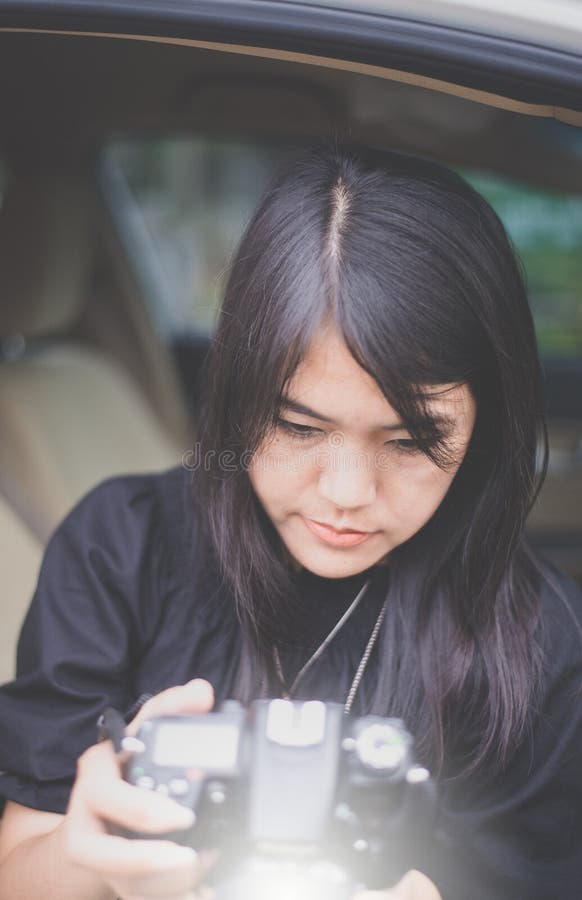 Schöner junger asiatischer Frauenphotograph, der Fotos überprüft und Digitalkamera hält lizenzfreies stockfoto Schöner junger asiatischer Frauenphotograph, der Fotos überprüft und Digitalkamera hält lizenzfreies stockfoto