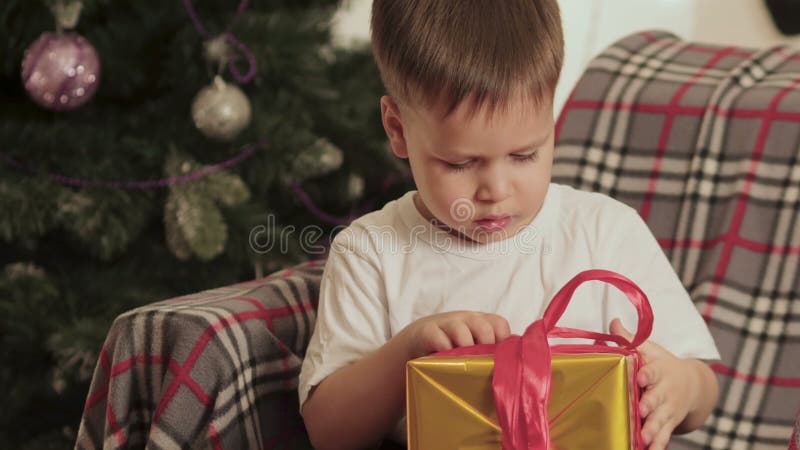 Schöner, kleiner Junge öffnet sein Weihnachtsgeschenk