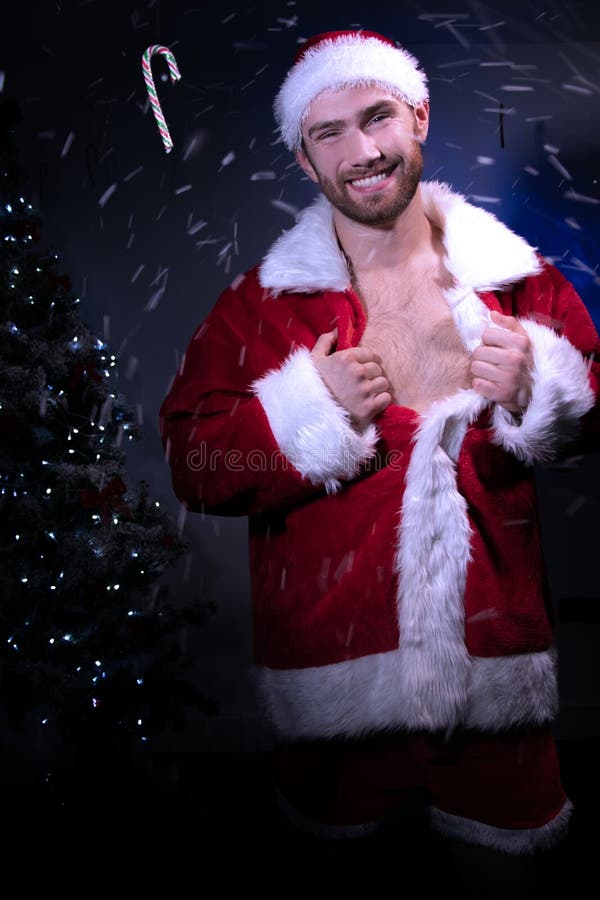 Schöner Mann Sankt zieht offen seine Jacke, die seinen Kasten mit Weihnachtsversuch im Hintergrund aufdeckt stockfotografie Schöner Mann Sankt zieht offen seine Jacke, die seinen Kasten mit Weihnachtsversuch im Hintergrund aufdeckt stockfotografie