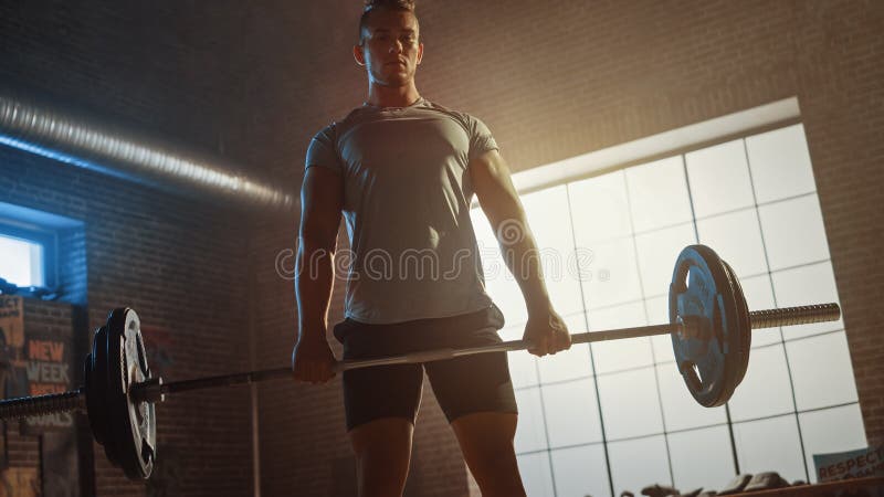 Schöner Muskelmann überragt mit einem Grill in einem kleinen, authentischen Fitnessraum. Sportler lizenzfreie stockfotos
