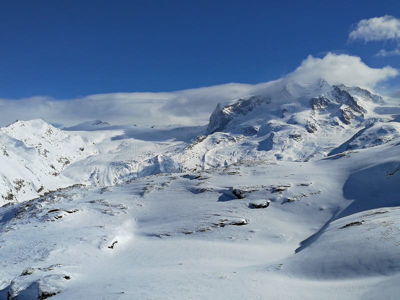 Schöner Panoramablick von Schnee-mit einer Kappe bedeckten Bergen mit Skisteigungen in den Schweizer Alpen nahe Zermatt, im Bezir stockbilder Schöner Panoramablick von Schnee-mit einer Kappe bedeckten Bergen mit Skisteigungen in den Schweizer Alpen nahe Zermatt, im Bezir stockbilder