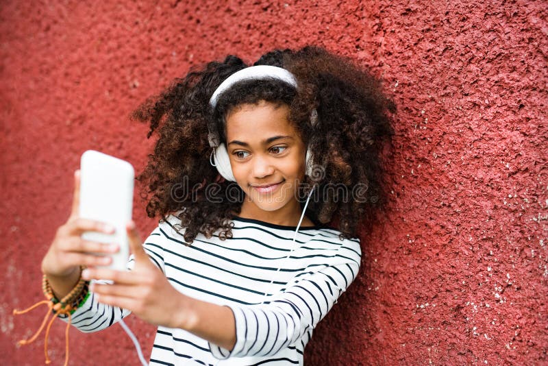 Schönes Afroamerikanermädchen mit dem intelligenten Telefon, das selfie nimmt stockfoto Schönes Afroamerikanermädchen mit dem intelligenten Telefon, das selfie nimmt stockfoto
