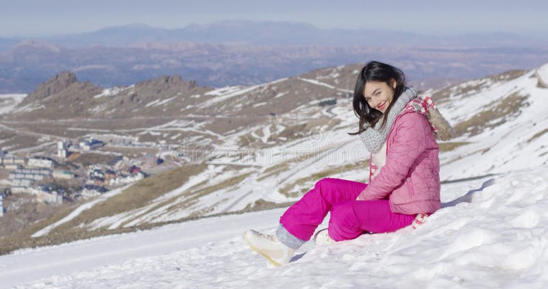 Schönes asiatisches Mädchen, das am Schnee sitzt