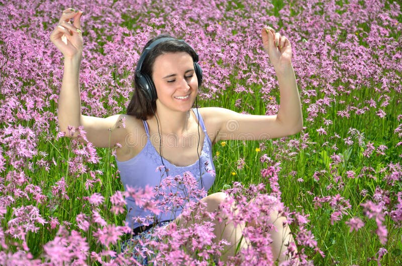 Schönes attraktives Brunettemädchen, das Musik mit Kopfhörern auf herrlicher Wiese hört stockfotografie Schönes attraktives Brunettemädchen, das Musik mit Kopfhörern auf herrlicher Wiese hört stockfotografie