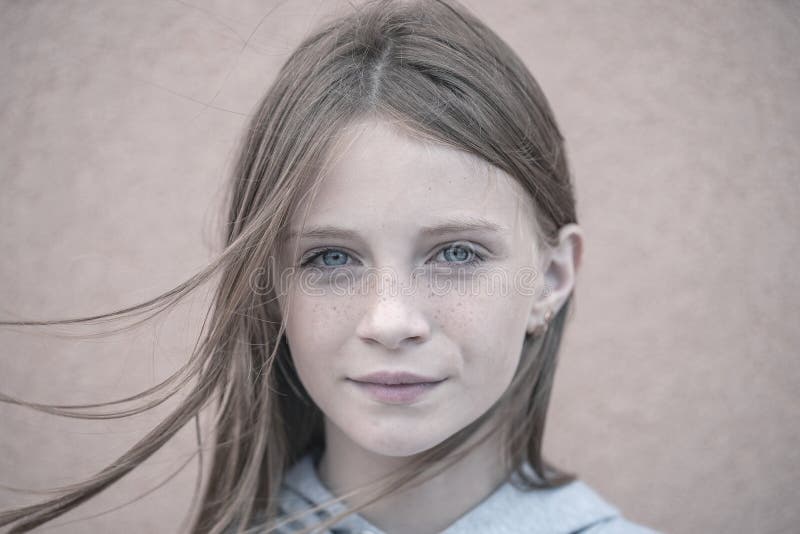 Beautiful blond young girl with freckles outdoors on wall background, close up portrait. Beautiful blond young girl with freckles outdoors on wall background, close up portrait