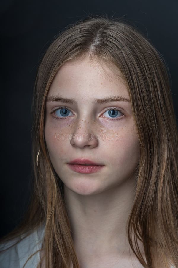 Charming blond young girl with freckles and blue eyes on a black background, indoors, close up portrait. Charming blond young girl with freckles and blue eyes on a black background, indoors, close up portrait