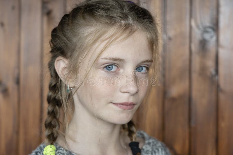 Beautiful blond young girl with freckles indoors on wooden background, close up portrait. Beautiful blond young girl with freckles indoors on wooden background, close up portrait