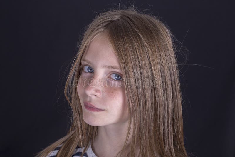 Beautiful blond young girl with freckles indoors on a black background, close up portrait. Beautiful blond young girl with freckles indoors on a black background, close up portrait