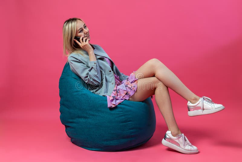Schönes blondes Mädchen in einem Matrosen und purpurrote sundress sitzt auf einem grünen Taschenstuhl mit ihren Beinen, die auf e stockfoto Schönes blondes Mädchen in einem Matrosen und purpurrote sundress sitzt auf einem grünen Taschenstuhl mit ihren Beinen, die auf e stockfoto