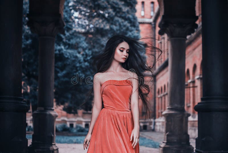 Schönes Brunettemädchen, mit dem sehr langen Haar, in einer Orange, Weinlesekleid