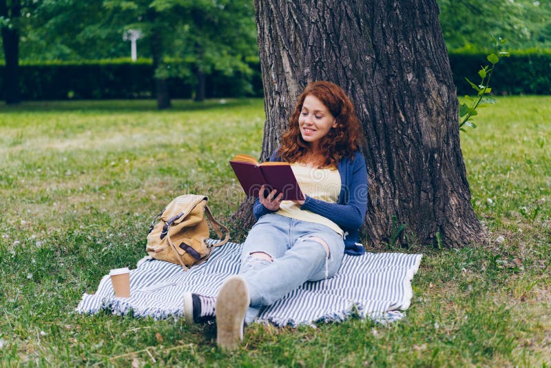 Schönes Buch der jungen Frau Lese, dasauf Decke unter Baum beim Parklächeln sitzt stockfoto Schönes Buch der jungen Frau Lese, dasauf Decke unter Baum beim Parklächeln sitzt stockfoto