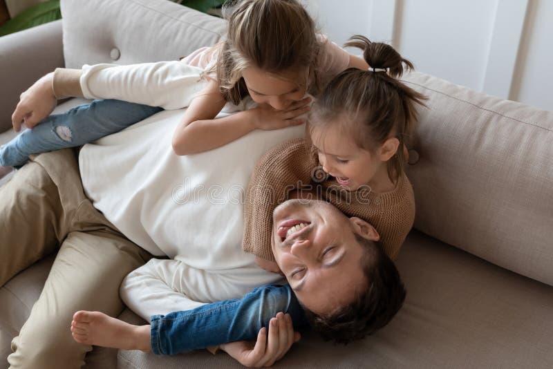 Schönes der Tochter zwei Spiel des Vaters, und das liegt auf der Couch stockfotografie
