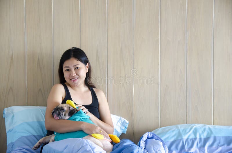 Schönes Familienwochenende Frauenruhe im Bett mit niedlichem Pughund lizenzfreie stockfotografie Schönes Familienwochenende Frauenruhe im Bett mit niedlichem Pughund lizenzfreie stockfotografie