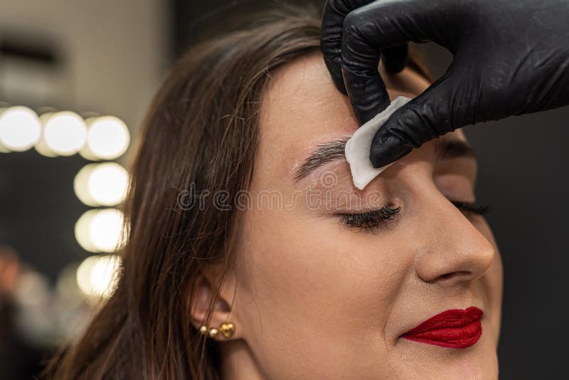Beautiful young girl in a salon where she is getting foam on her eyebrows to degrease them. The concept of eyebrow lamination. Beautiful young girl in a salon where she is getting foam on her eyebrows to degrease them. The concept of eyebrow lamination