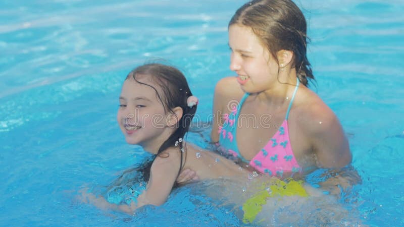 Schönes junges Mädchen unterrichtet ihre kleine Schwester, im Pool zu schwimmen