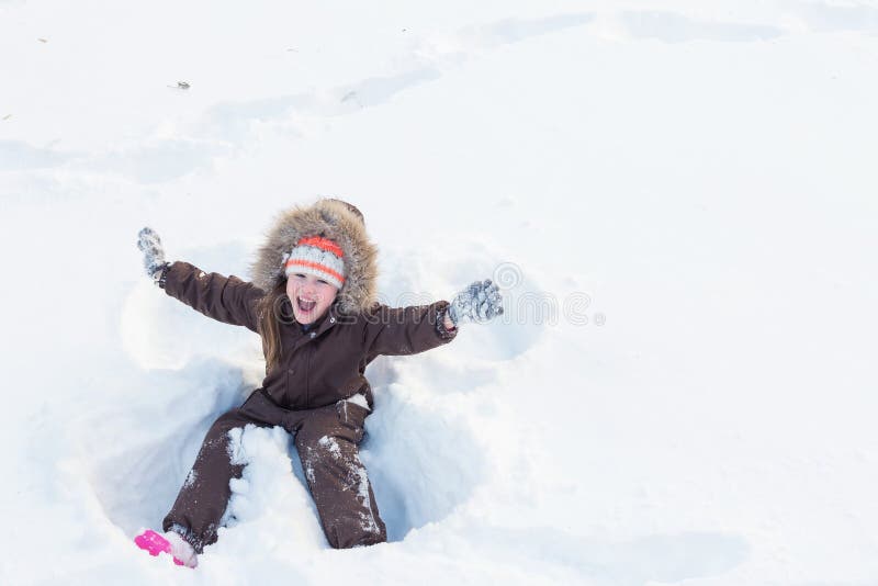 Schönes kleines Mädchen, das einen Schneeengel macht stockfotografie Schönes kleines Mädchen, das einen Schneeengel macht stockfotografie