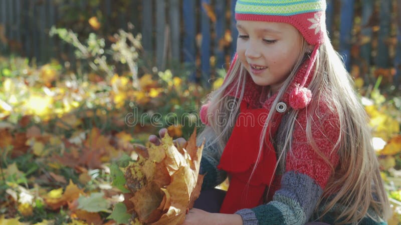 Schönes, kleines Mädchen, das mit Herbst, gelbe Blätter im Park spielt Das Konzept des Herbstes