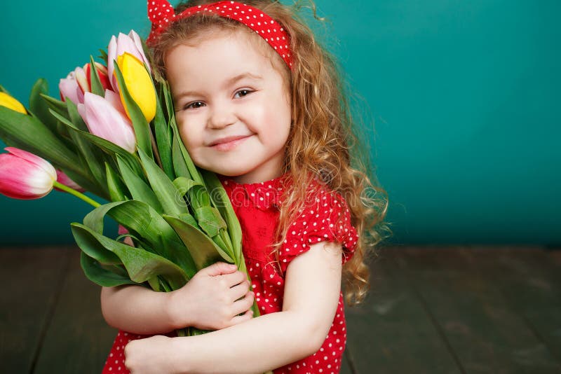 Schönes kleines Mädchen mit einem großen Blumenstrauß von Tulpen lizenzfreie stockfotos Schönes kleines Mädchen mit einem großen Blumenstrauß von Tulpen lizenzfreie stockfotos