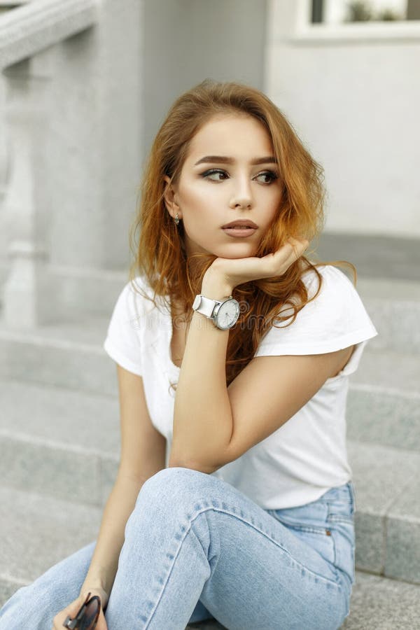 Schönes Mädchen, das auf den Schritten sitzt und zur Seite schaut stockfoto Schönes Mädchen, das auf den Schritten sitzt und zur Seite schaut stockfoto